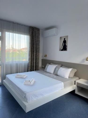 a bedroom with a large white bed with a window at Satmar in Lozenets