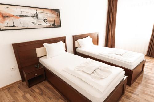 two beds in a room with white sheets at Hotel Centrum Prizren in Prizren
