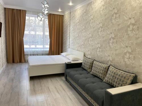 um quarto com uma cama, um sofá e uma janela em Эксклюзив-404 em Astana