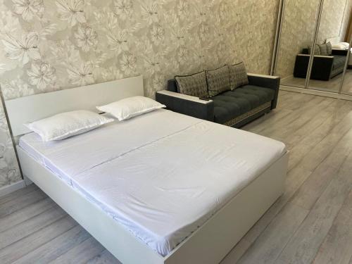 uma cama branca e um sofá num quarto em Эксклюзив-404 em Astana