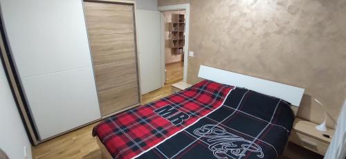 a bedroom with a bed with a plaid blanket on it at Lui Apartment in Novi Grad