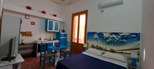 a bedroom with a blue bed and a kitchen at Casetta Colorata in Bagheria