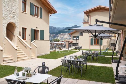 a patio with tables and chairs and an umbrella at June Stay Lake Garda in Brenzone sul Garda