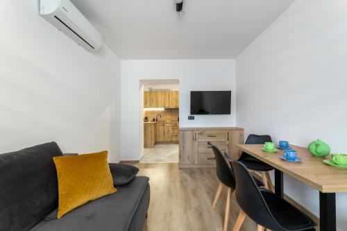 ein Wohnzimmer mit einem Sofa und einem Tisch mit Stühlen in der Unterkunft Apartament Centrum A in Kudowa-Zdrój