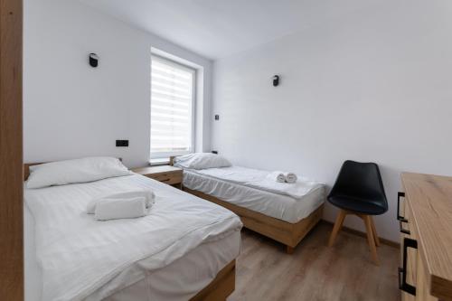 2 Betten in einem Zimmer mit einem Schreibtisch und einem Stuhl in der Unterkunft Apartament Centrum A in Kudowa-Zdrój