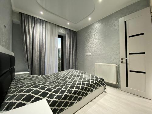 a bedroom with a black and white bed and a window at Comfort Home in Tbilisi City