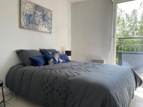 um quarto com uma cama com almofadas azuis e uma janela em Appartement T3, Terrasse, Piscine, 2 Places Parking Privé em Onet le Château