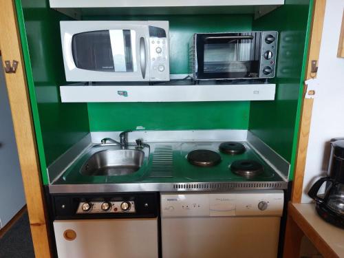 une petite cuisine avec un évier et un micro-ondes dans l'établissement Duplex 2 pièces à Arc 1800 avec WiFi, cuisine équipée et casier à ski - FR-1-411-191, à Arc 1800