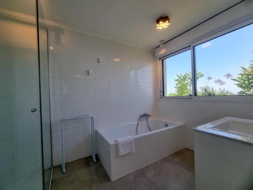 ein weißes Bad mit einer Badewanne und einem Fenster in der Unterkunft Villa La Turbie Vue Panoramique in La Turbie