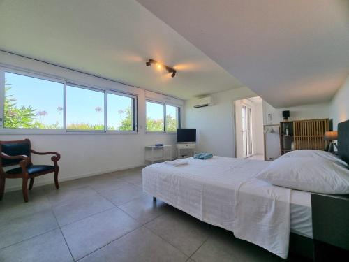 Schlafzimmer mit einem Bett, einem Stuhl und Fenstern in der Unterkunft Villa La Turbie Vue Panoramique in La Turbie