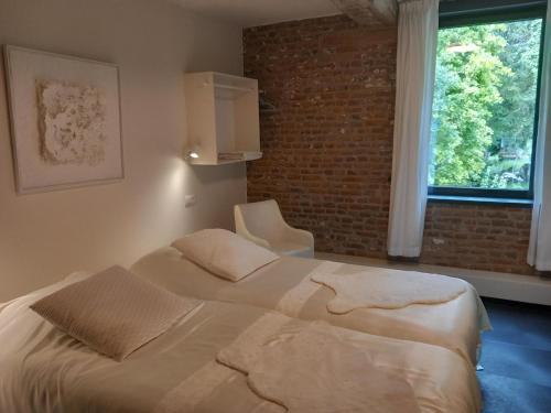 a bedroom with a bed and a brick wall at Meschermolen, overnachten in de schuur in Eijsden