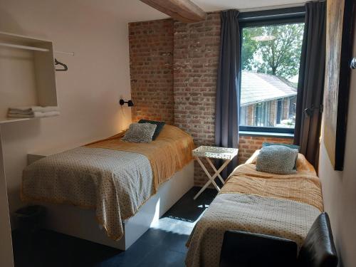 um quarto com 2 camas e uma janela em Meschermolen, overnachten in de schuur em Eijsden