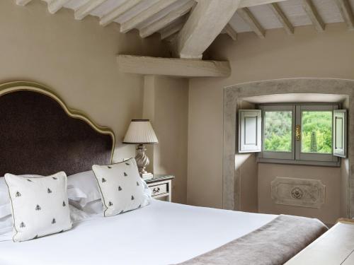 a bedroom with a white bed and a window at Villa di Piazzano - Small Luxury Hotels of the World in Cortona