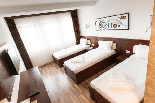 a hotel room with two beds and a tv at Hotel Centrum Prizren in Prizren