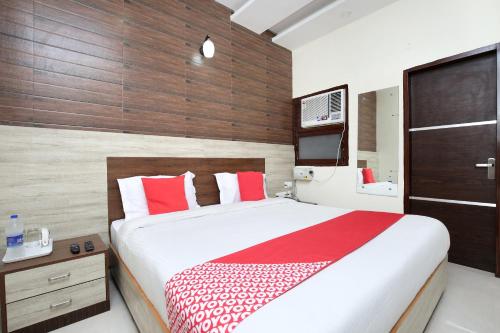 una camera da letto con un grande letto con cuscini rossi e bianchi di OYO Hotel Prabhat a Zirakpur