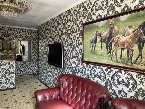a living room with a painting of horses on the wall at Тумар in Osh