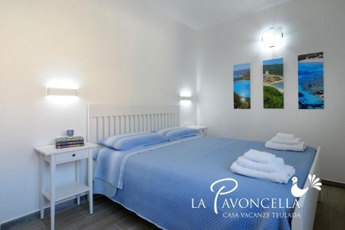 a bedroom with a blue bed and a white table at Case Vacanze La Pavoncella in Teulada