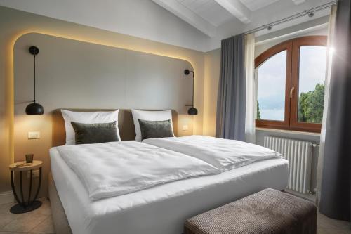 ein Schlafzimmer mit einem großen weißen Bett und einem Fenster in der Unterkunft June Stay Lake Garda in Brenzone sul Garda