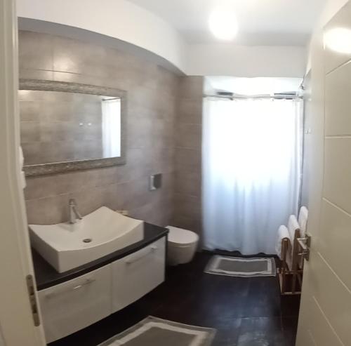 een badkamer met een wastafel, een toilet en een spiegel bij Aloe Apartment in Epidaurus in Oud Epidauros