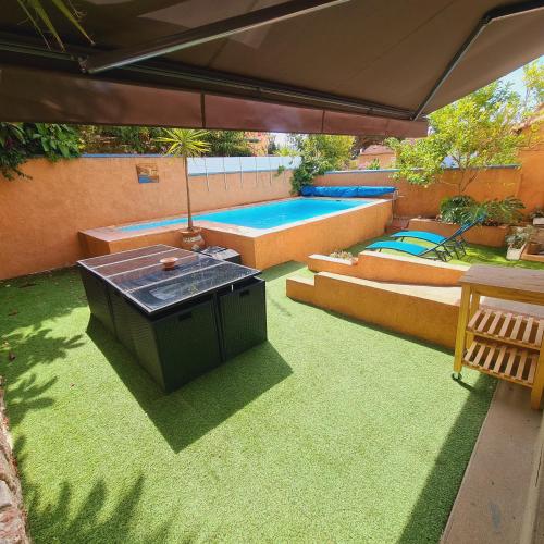 un patio avec un parasol et une piscine dans l'établissement Villa standing 10 personnes piscine/ pinède, à Canet
