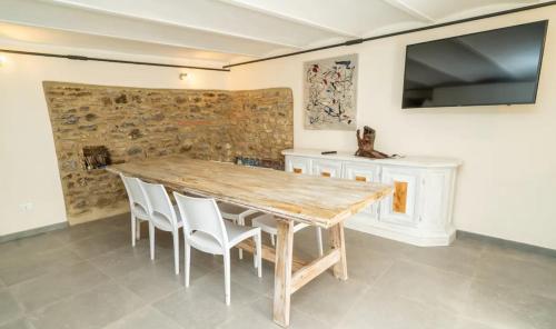 a wooden table with white chairs and a television on a wall at Borgo degli Artisti boutique rooms in Serricciolo