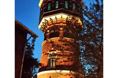 een hoge toren met een klok erop bij Renovated luxury water tower within walking distance of the beach boulevard in Vlissingen
