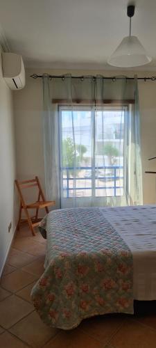 een slaapkamer met een bed en een groot raam bij Tavira Pimpão - Sea View Flat in Tavira