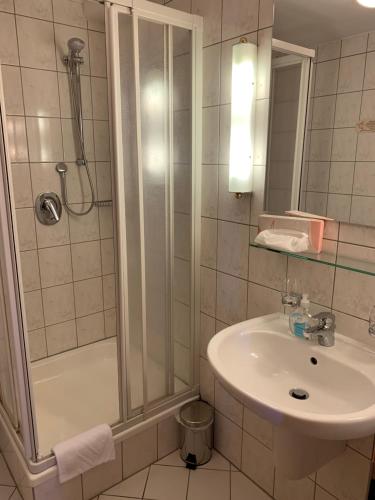 a white bathroom with a shower and a sink at Hotel Garni Eschenbach in Hildburghausen