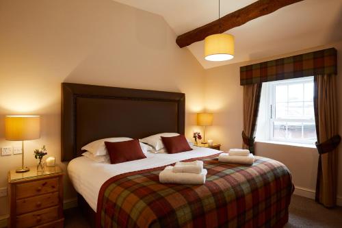 a bedroom with a large bed with two towels on it at Macdonald Plas Talgarth Resort in Pennal