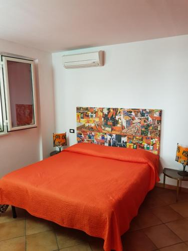 ein Schlafzimmer mit einem Bett mit einer orangefarbenen Tagesdecke in der Unterkunft Calipso in Bagheria