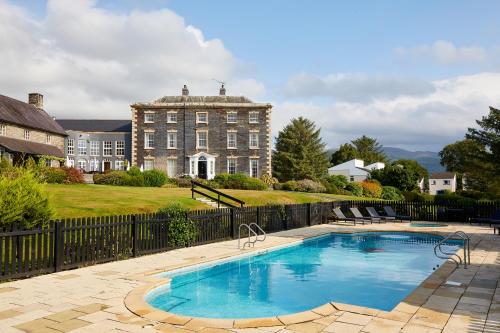 a swimming pool in front of a large building at Macdonald Plas Talgarth Resort in Pennal