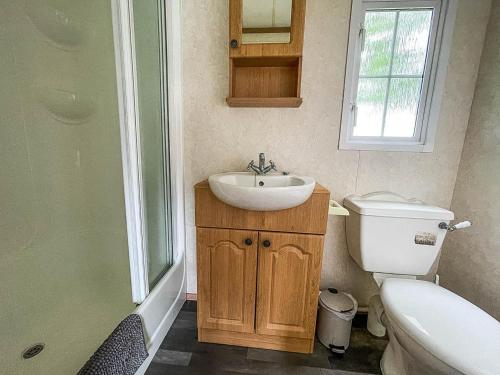 a bathroom with a sink and a toilet and a window at Superb Caravan With Decking At Southview Holiday Park Ref 33093s in Skegness