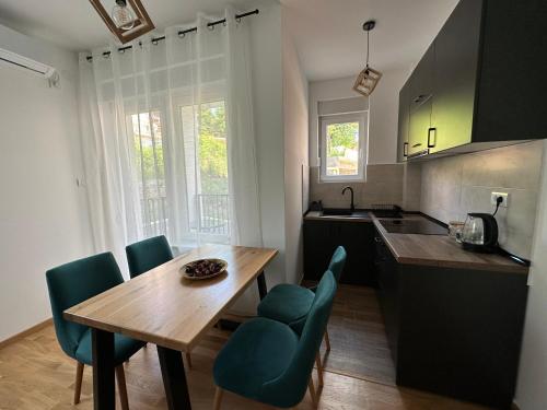 a kitchen with a wooden table and green chairs at Apartman Pavlović in Soko Banja