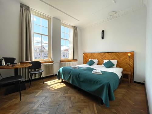 a bedroom with a bed and a table and windows at Hector Zierikzee in Zierikzee