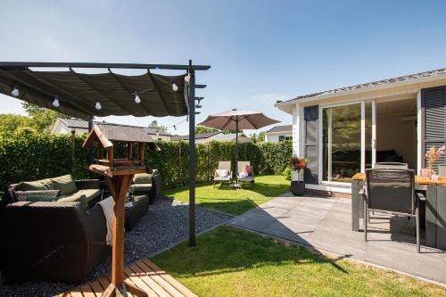 a patio with an umbrella and a table and chairs at 68, Stijlvol & Rustig Tuinverblijf met Lounge & Airco! Nabij Efteling in Oisterwijk