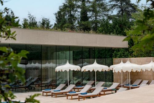 a group of chairs and umbrellas in front of a building at Cowley Manor Experimental in Cheltenham