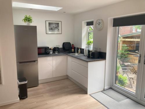 a kitchen with white cabinets and a large window at Beautiful detached private annex in great location in Manchester