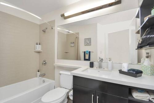 a white bathroom with a sink and a toilet and a tub at Studio Apt: Heart of Houston in Houston