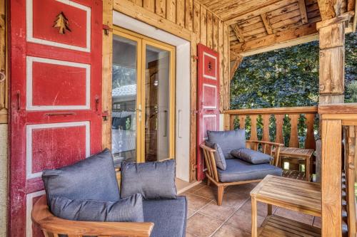- une terrasse couverte avec 2 chaises, une table et une porte rouge dans l'établissement Panorama du Mont-Blanc- Spacious and ideally located 1 bedroom apartment, à Chamonix-Mont-Blanc