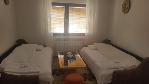 - 2 lits dans une chambre avec une table et une fenêtre dans l'établissement Oaza Mira, à Sarajevo