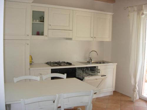 a kitchen with white cabinets and a sink and a table at Agriturismo Maso Bergot in Arco