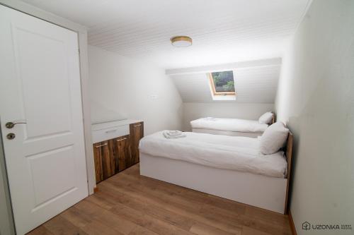 um pequeno quarto com 2 camas e uma porta em Uzonka Guesthouse em Ozunca-Băi