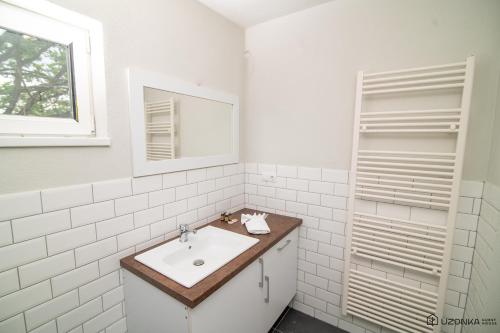 a white bathroom with a sink and a mirror at Uzonka Guesthouse in Ozunca-Băi