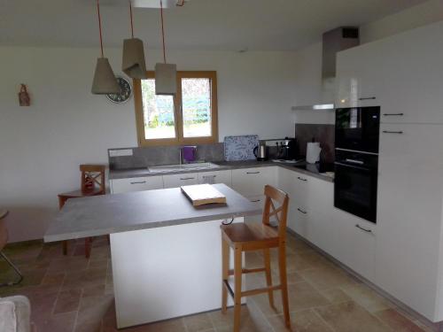 eine Küche mit einer Theke, einem Tisch und Stühlen in der Unterkunft gîte les jardins d'esteban in Tourville-sur-Sienne