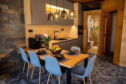 a kitchen and dining room with a wooden table and blue chairs at Apartmán Hrabušice in Hrabušice