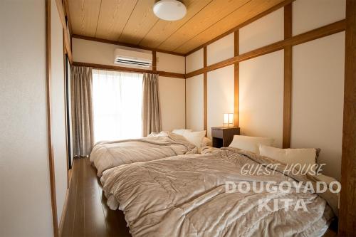 um quarto com uma cama grande e uma janela em GUEST HOUSE DOUGOYADO KITA em Matsuyama