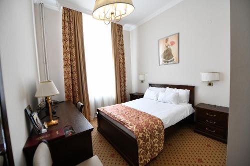 a hotel room with a bed and a desk and a window at Hotel Beograd in Čačak