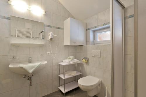 a white bathroom with a sink and a toilet at Chalet Helene in Mayrhofen