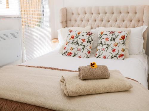 a bedroom with a white bed with a flower patterned pillows at Garden Suite in Dronfield