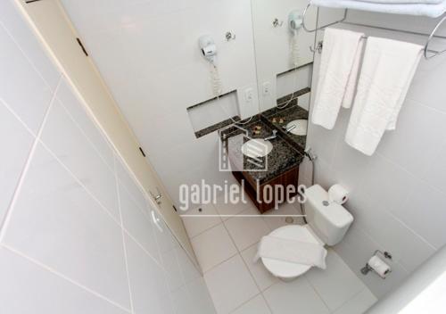 a white bathroom with a toilet and towels at Lacqua Di Roma - O apartamento dos seus sonhos com desconto especial! in Caldas Novas